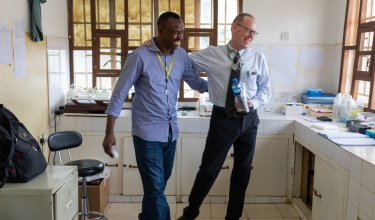 Paul Farmer walks with Musa Bangura, head of laboratory services for PIH-Sierra Leone, at Koidu Government Hospital.