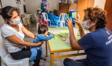 A family receives health advice from a community health worker in Peru
