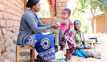 Community Health Worker Annie Jere visits with Milica Steven and her three children at their home in Neno, Malawi, screening the family for health concerns.