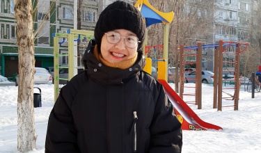 Maya, a patient in Kazakhstan who accessed tuberculosis care through Partners In Health and the endTB project, stands outside of a playground in a black winter hat and coat.