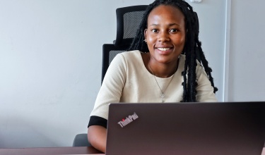 Mankopane Moeletsi smiling while sitting at a desk with laptop