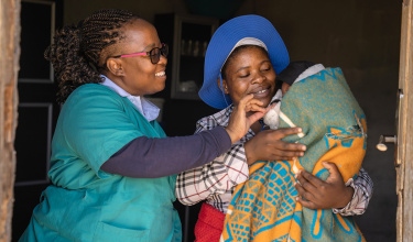 Mother holding baby, alongside clinical staff member in Lesotho