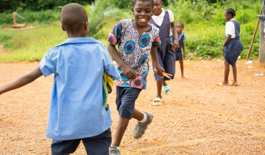Dennis Toe smiles and runs alongside his classmates